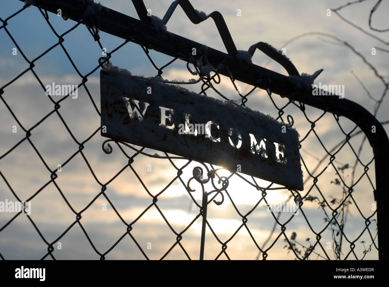 Welcome sign on fence gate in garden with sunlight shining through Stock Photo