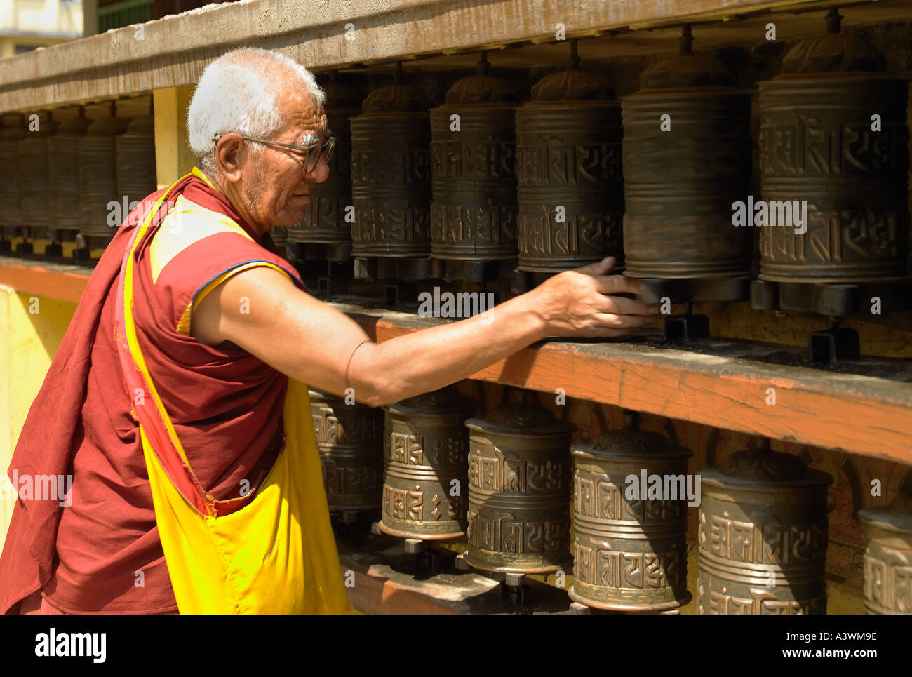 Monk turning a preyer wheel at Boudhanath Buddhist Temple in Kathmandu, Nepal Stock Photo