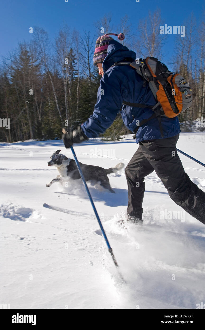 A backcountry skier and his dog move through powder lake effect snow