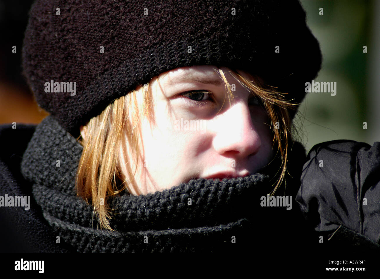 Young Caucasian woman hiding from the cold at antii War demonstration in Atlanta State Capital in Winter with face wrap and knit cap blond Stock Photo