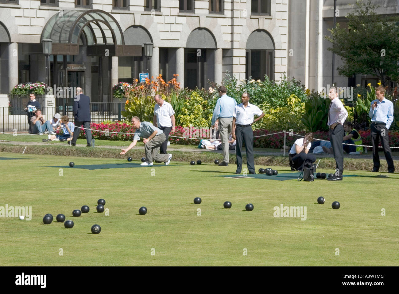 Lunchtime game of bowls on bowling green watched by office workers on a hot summers day Finsbury Square London England UK Stock Photo
