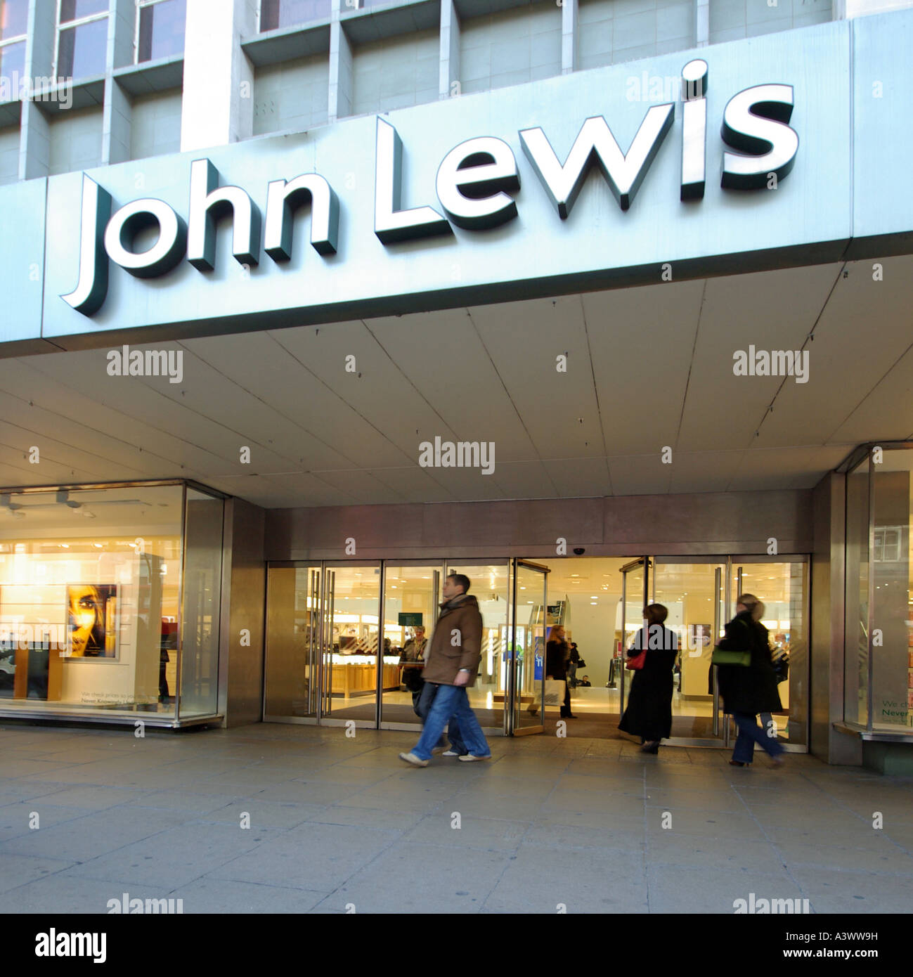 Shopping street scene shoppers at John Lewis retail business department store main entrance doors sign above Oxford Street West End London England UK Stock Photo