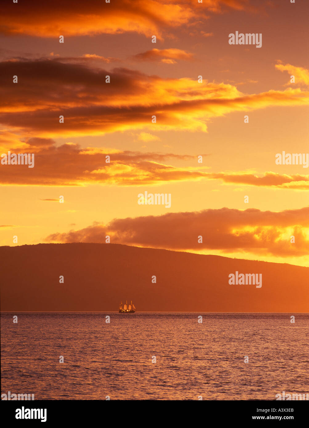 F00135M tiff Backlit old time sailing ship at sunset Island of Lanai in back Shot from Maui Hawaii Stock Photo