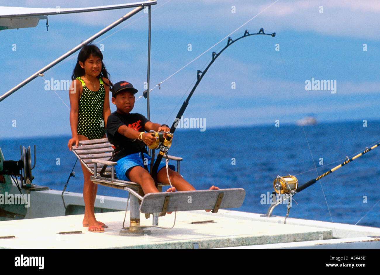 Boy fishing from boat off Kona Hawaii USA Stock Photo