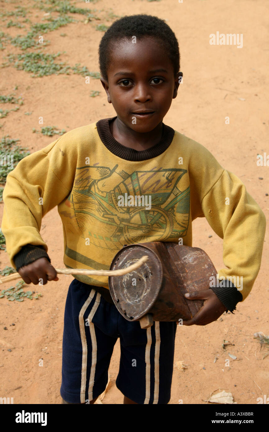 Boy using old rusty can and stick as a drum , Togoville, Togo Stock Photo