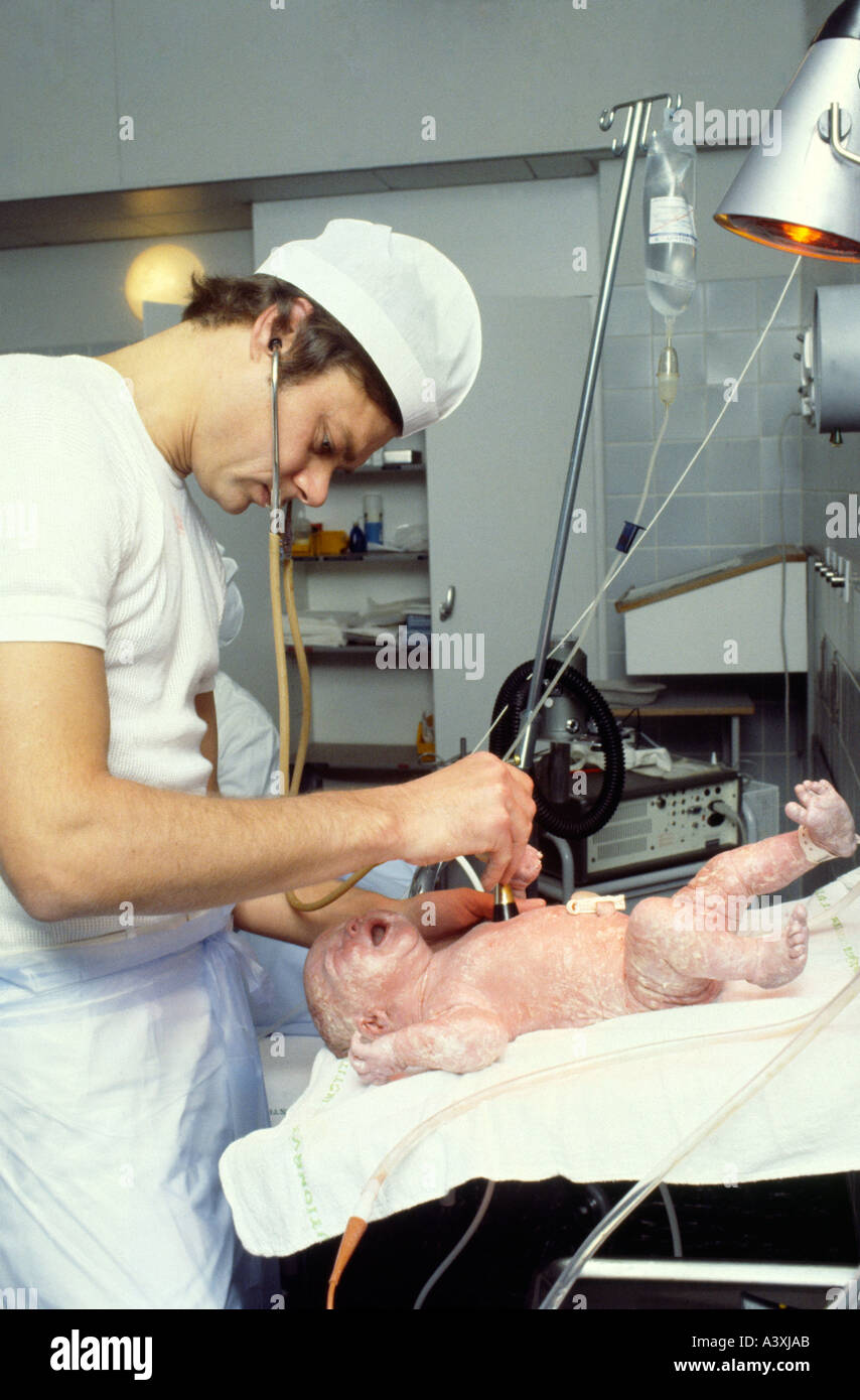 A young doctor checking hearth and lungs of a newborn boy Stock Photo