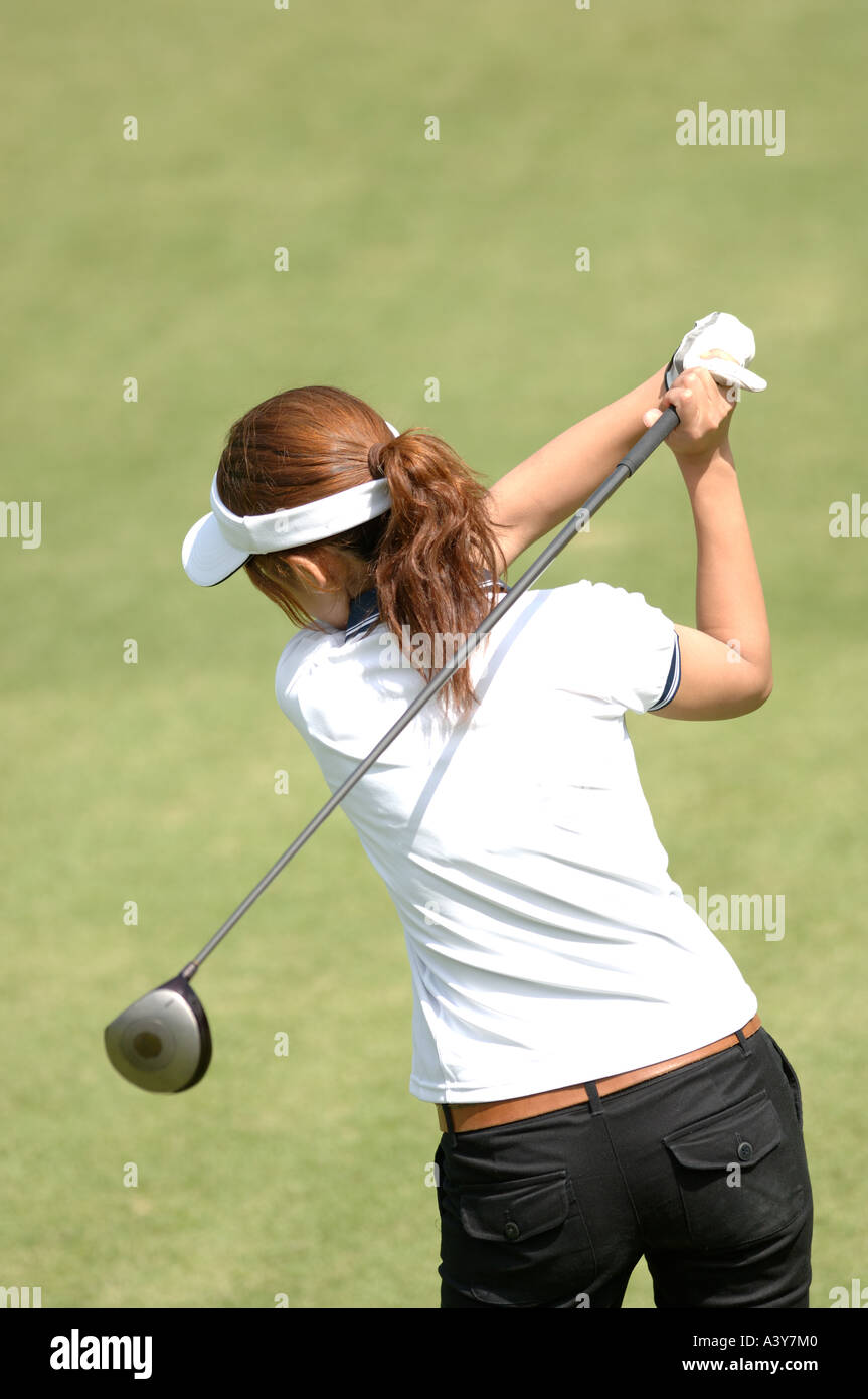 Rear view of a female golfer playing a shot Stock Photo