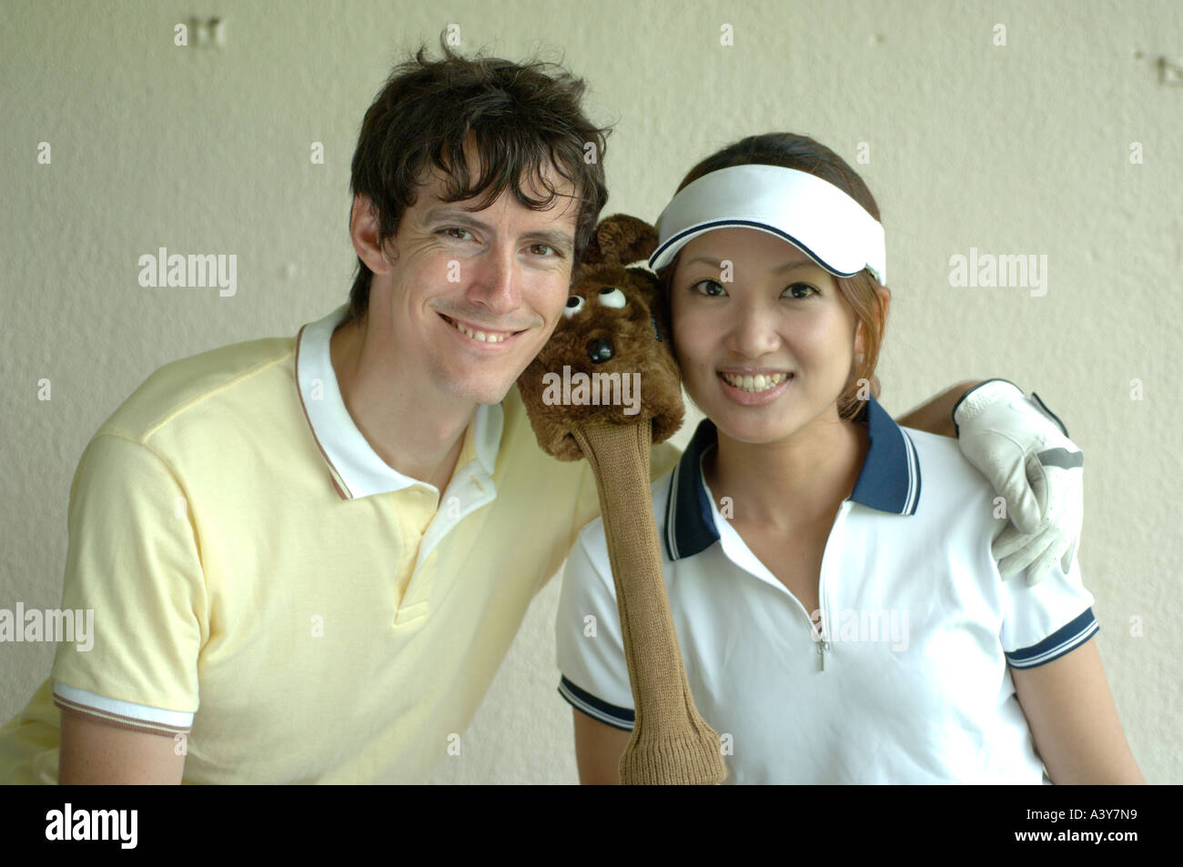 A couple smiles at the camera with a cute club cover in between them Stock Photo