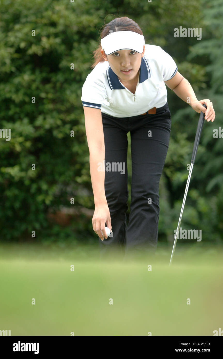 Woman bending to place a golf ball Stock Photo - Alamy