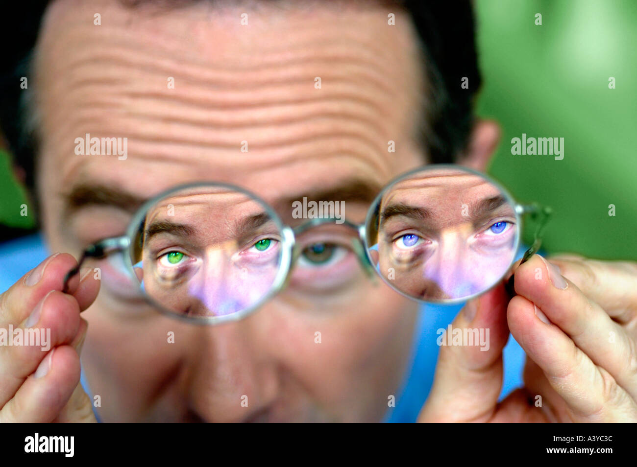 MR Man looking through his glasses with blue and green eyes Stock Photo