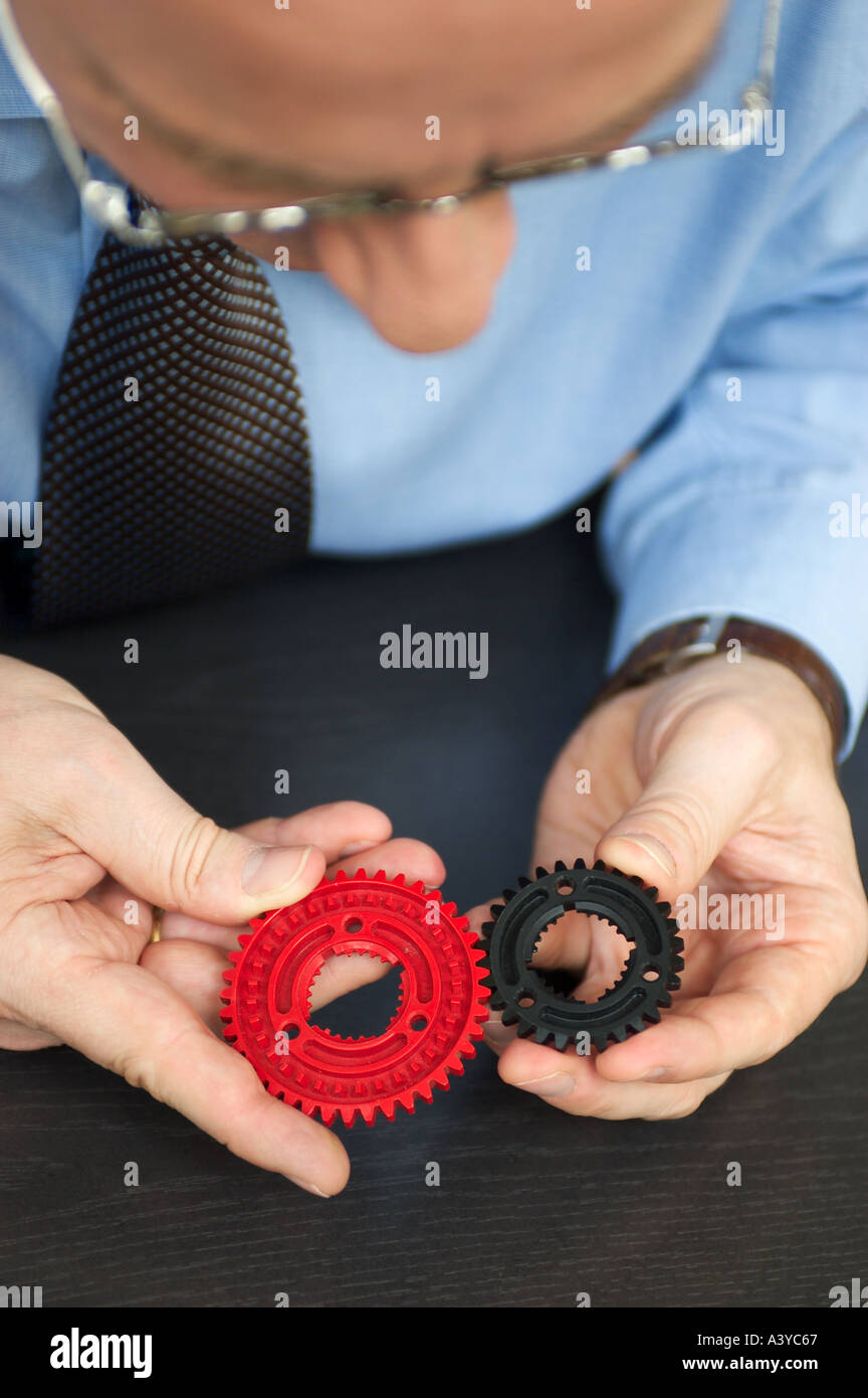 MR Exact control man holding two cogwheels in his hands Stock Photo