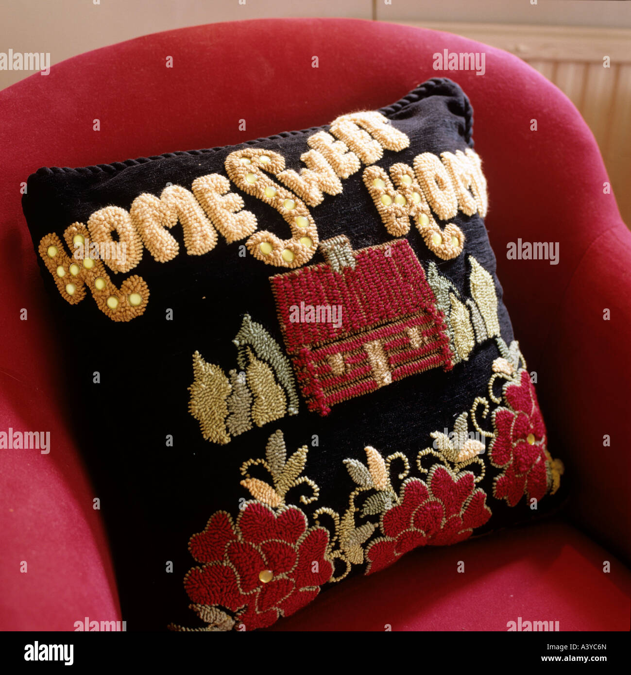 Hand-made cushion with writing Home Sweet Home on red armchair Stock Photo