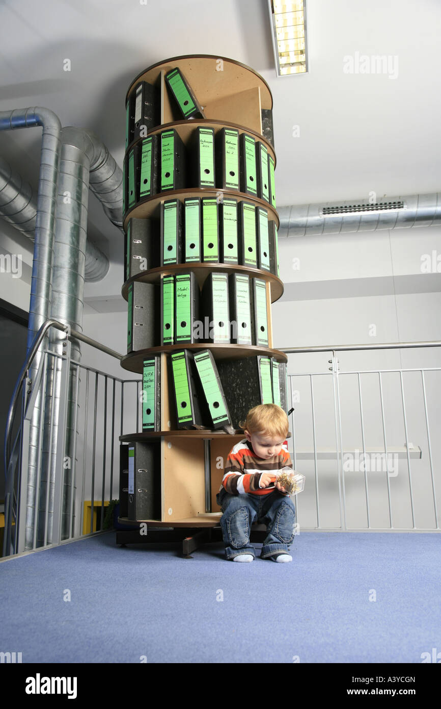 samll boy in the office, sitting in front of a foler storage rack Stock ...