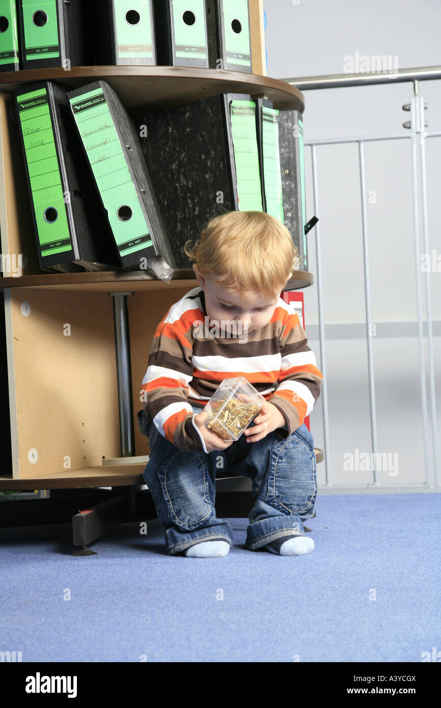 small boy in the office, sitting in front of a foler storage rack Stock ...