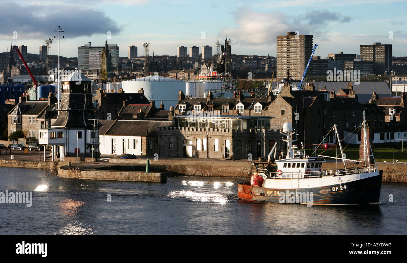 A fishing boat leaving Aberdeen Harbour with Fittie and Aberdeen skyline in background Stock Photo