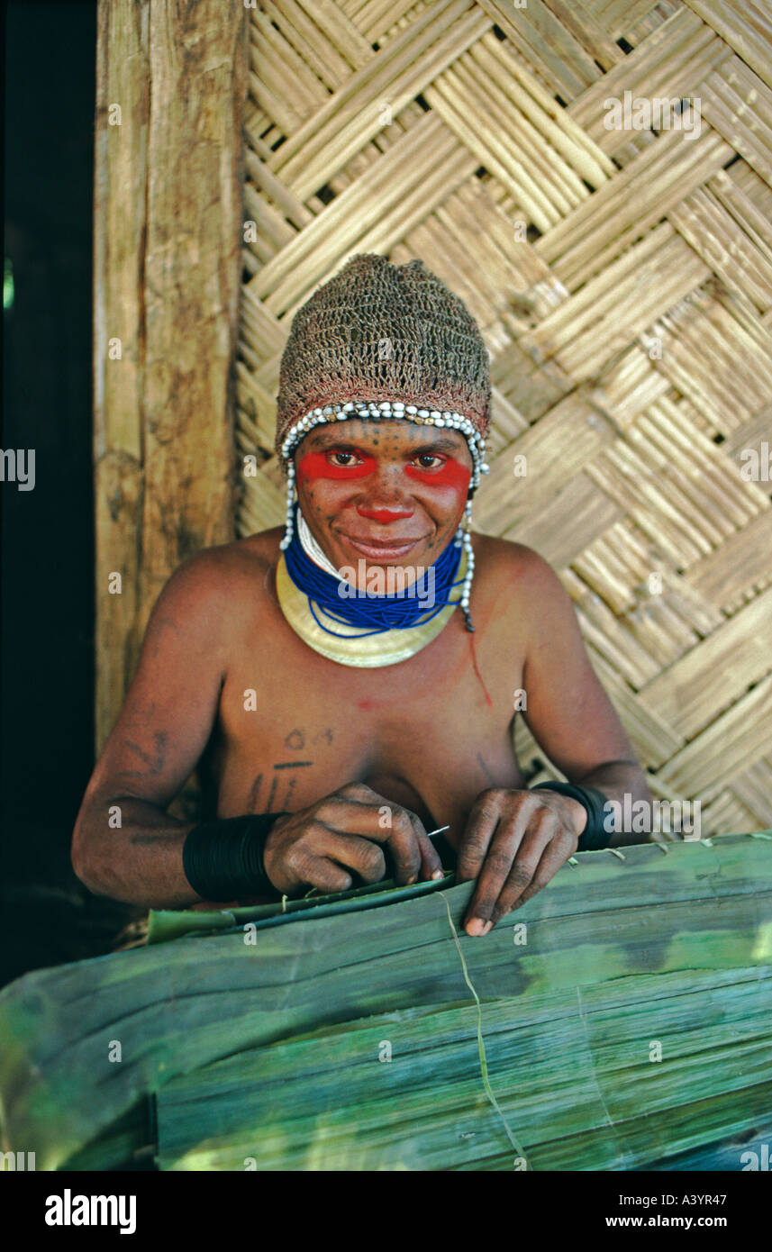 A Huli woman outside her house stitching cane leaves together to make a rain coat Tari Southern Highlands Papua New Guinea Stock Photo