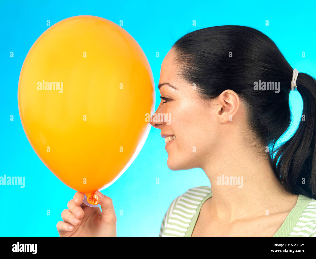Young Woman Holding Coloured Inflated Balloons Against A Blue ...