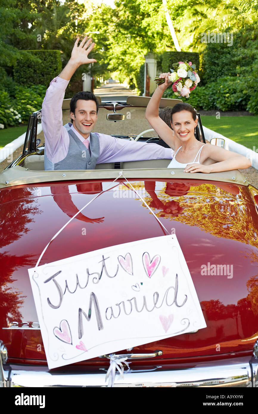 Mid adult bride and groom in retro car, waving hands Stock Photo - Alamy