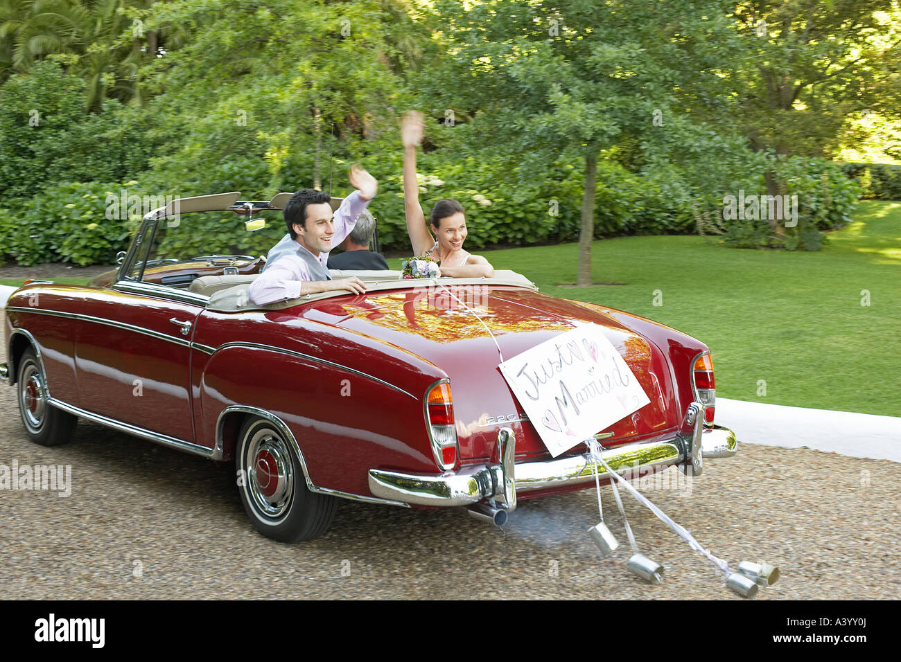 Mid adult bride and groom in vintage car, waving hands Stock Photo - Alamy