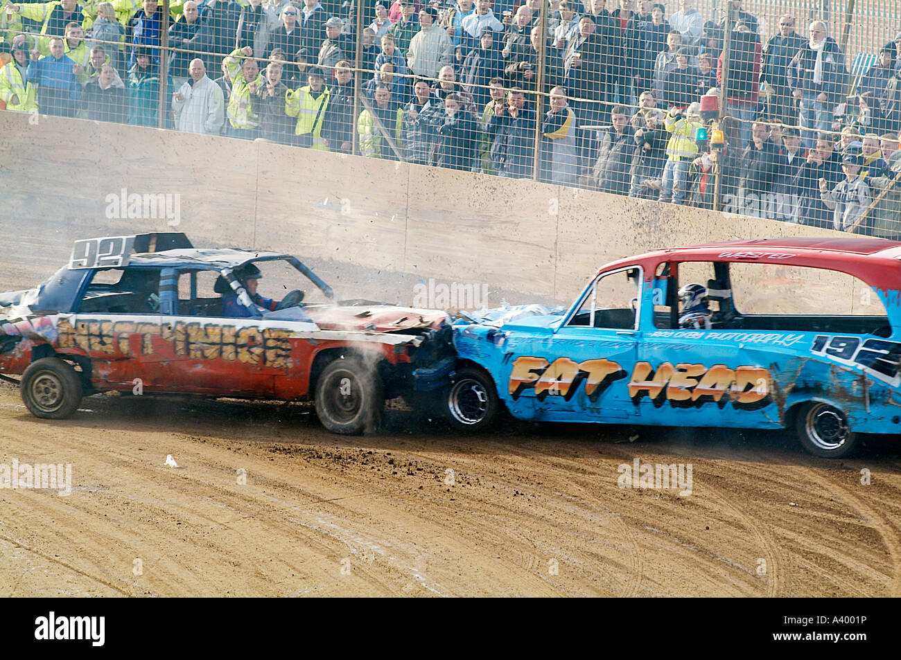 head on crash between two banger racing cars. Fat head is racing an old hearse and nutty nige is driving a cadillac Stock Photo