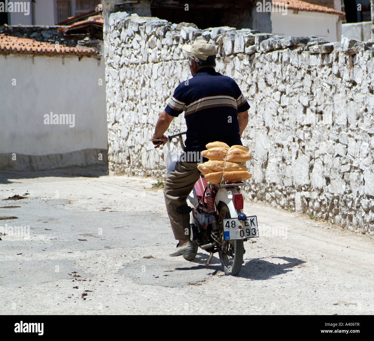 man carrying bread on moped Stock Photo