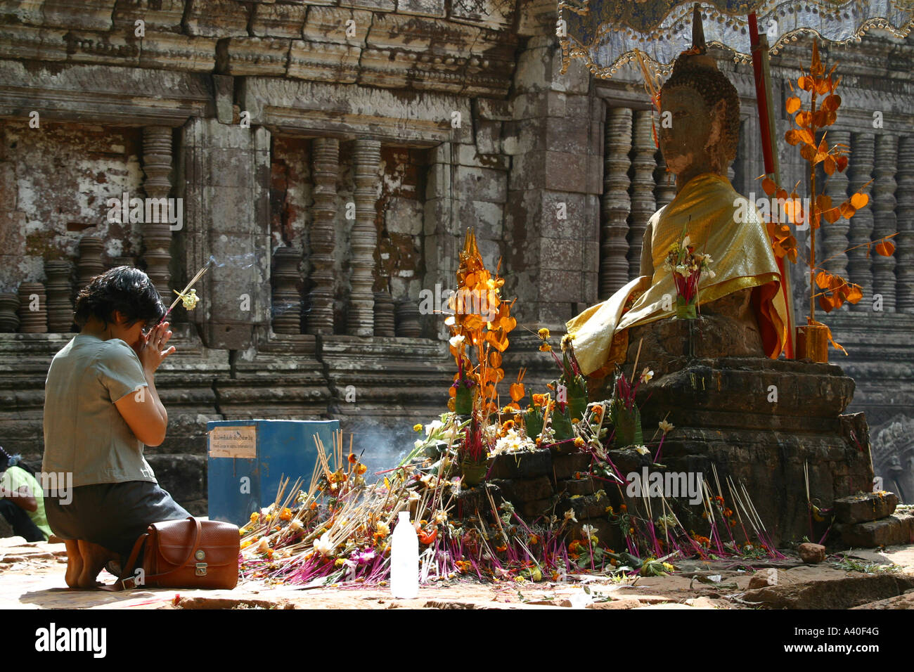 young buddhist woman praying in front of a buddha statue at the temple Wat Phou Stock Photo