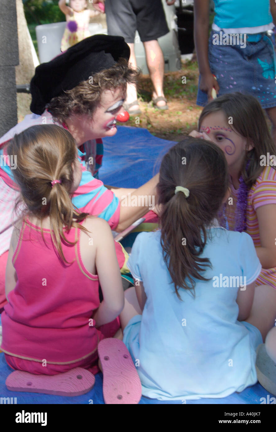 A Clown paints the faces and arms of children at a family picnic Stock Photo