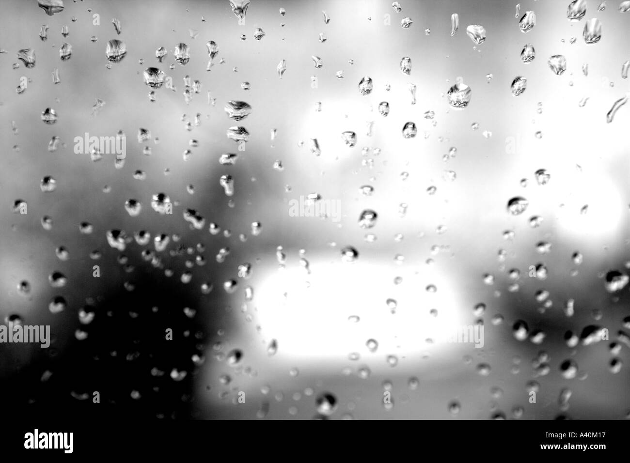 LOOKING OUT TO A GARDEN AS THE SUN APPEARS AFTER THE RAIN WITH RAINDROPS ON WINDOW Stock Photo