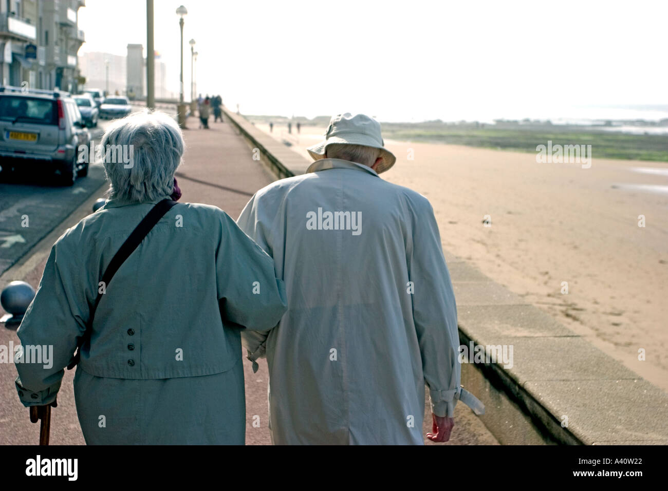 retired older couple 70s 75s 80s 85s holding hands and walking on a front of beach in sables d olonne vendee in france Stock Photo