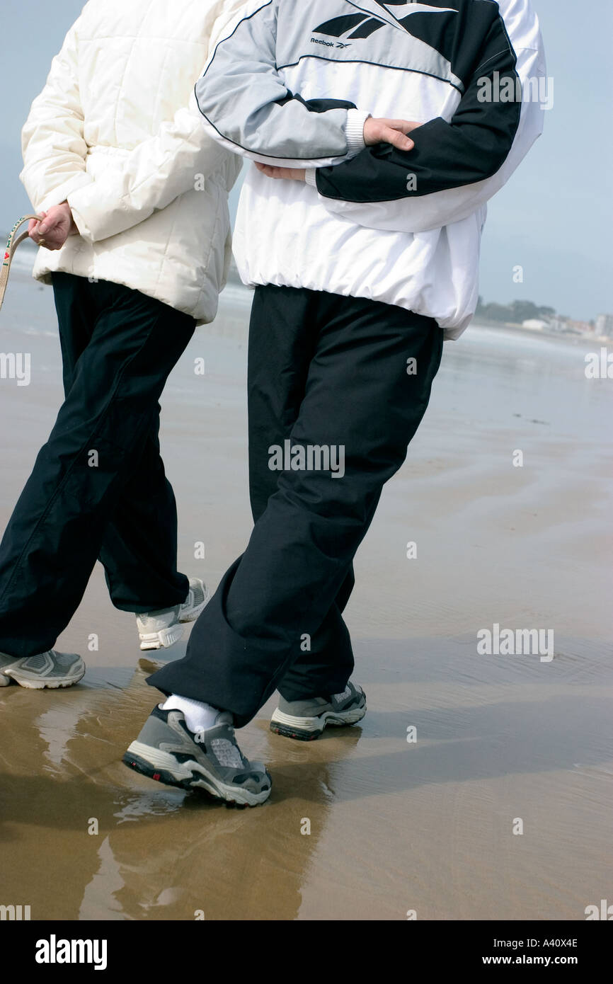back of a couple walking on the sand of sables d olonne beach in winter morning with sport clothes Stock Photo