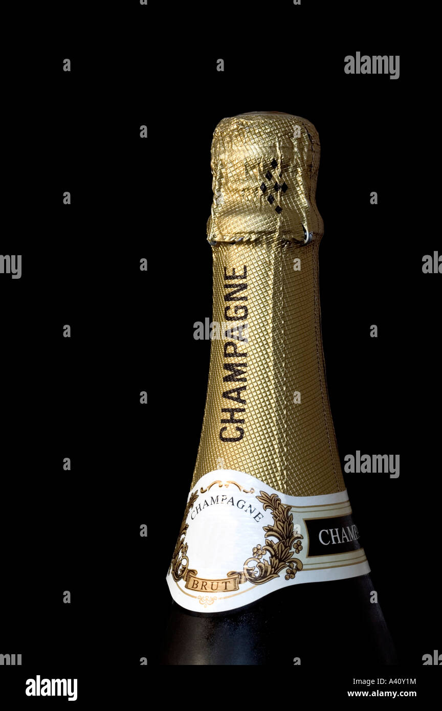 Champagne bottle top wrapped in gold foil isolated against a black background Stock Photo