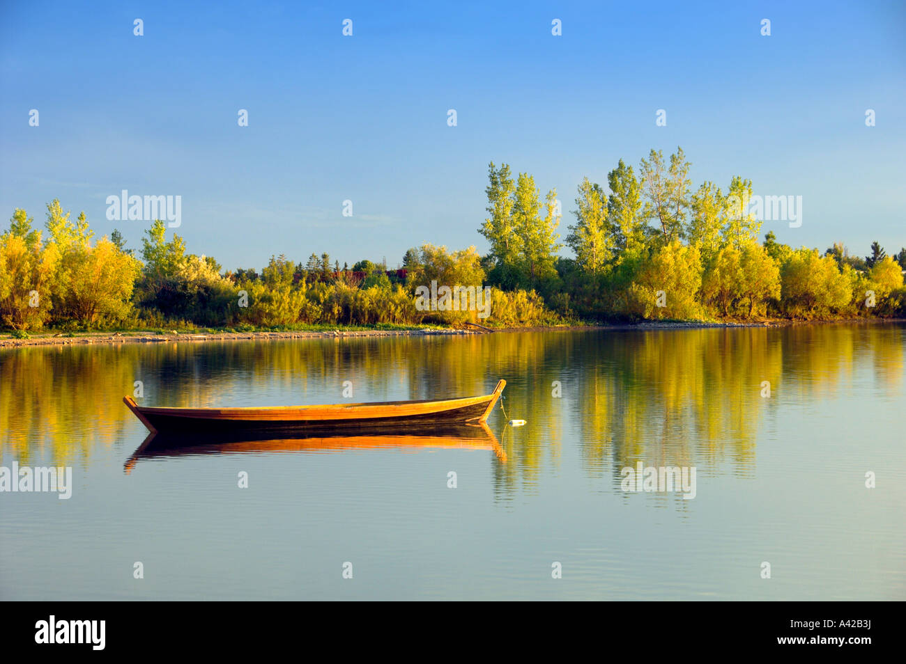 An old wooden boat anchored on a small calm lake at the Fort Whyte Nature Center in Winnipeg Manitoba Canada Stock Photo
