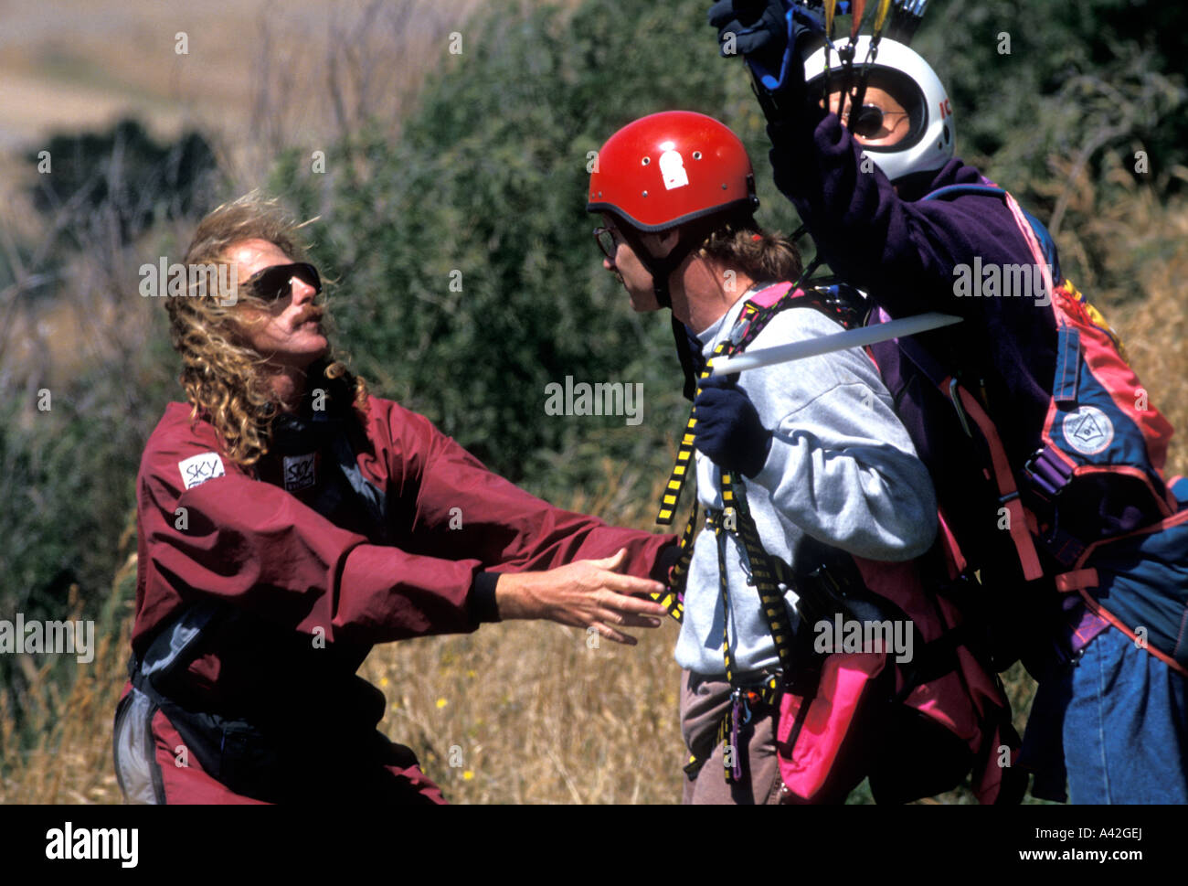 Parapenting instructor helping a novice who is just about to go up on a tandem flight Stock Photo