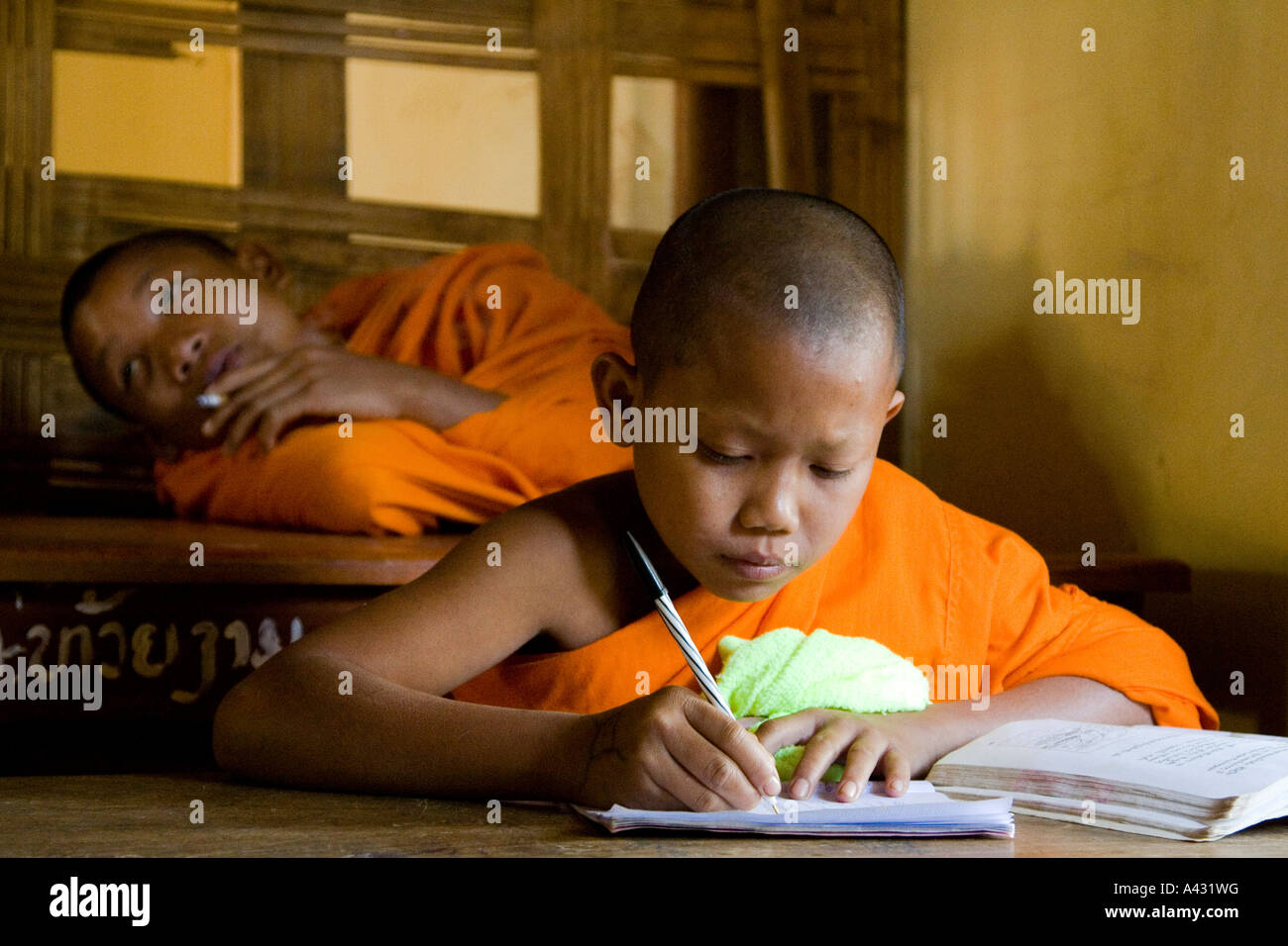 Novice Monk Smoking, another Studying at the Wat Kang School Vang Vieng Laos Stock Photo
