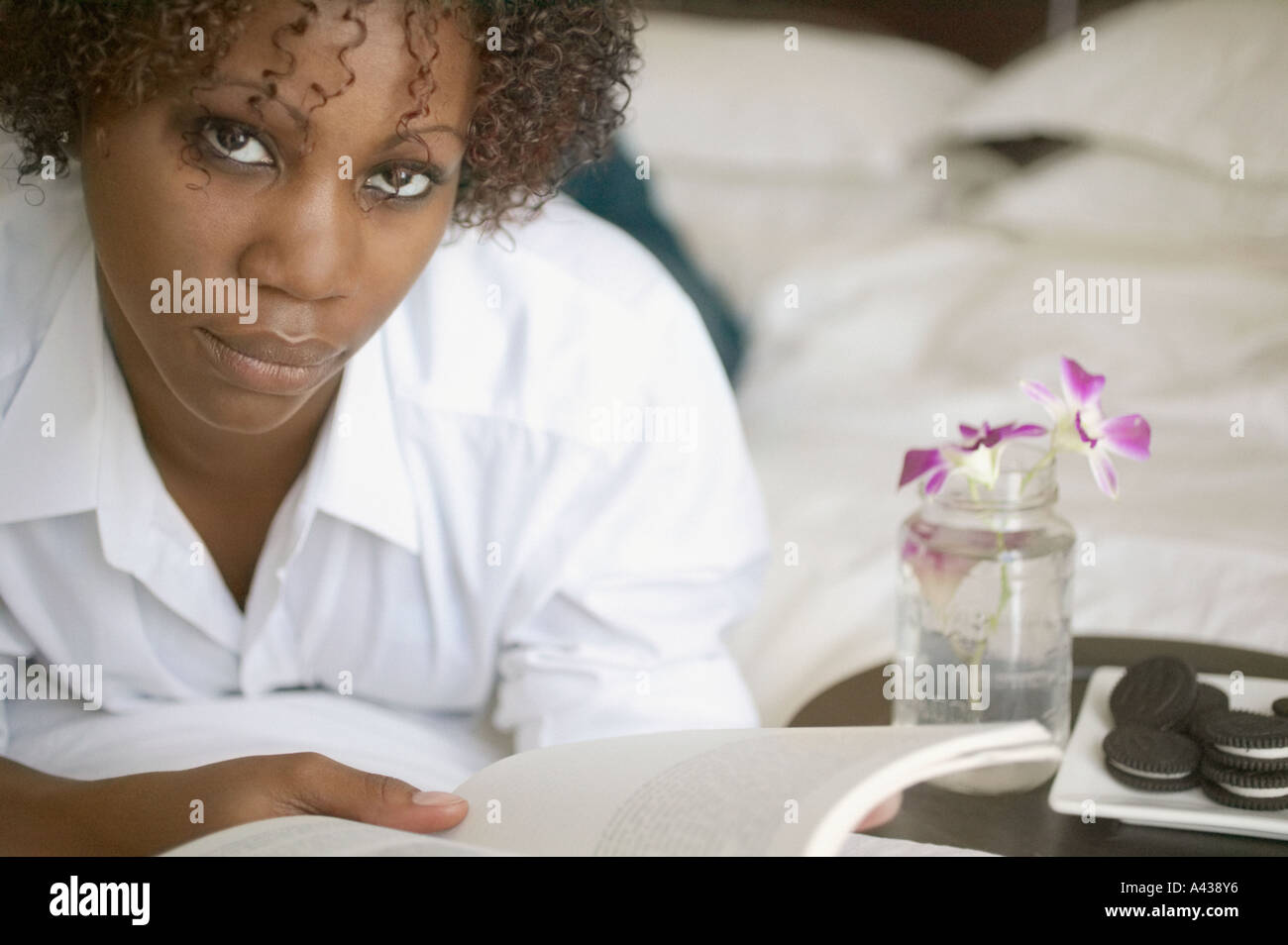 Portrait of woman on bed reading book Stock Photo