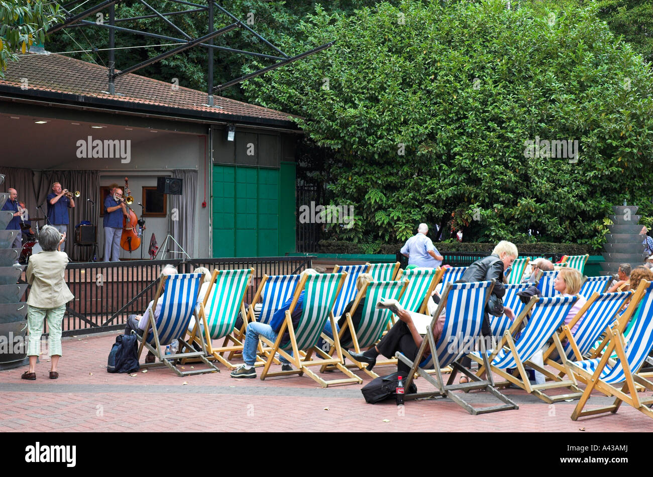 People sit in deckchairs to listen to Jazz at lunch time in a central London park. Stock Photo