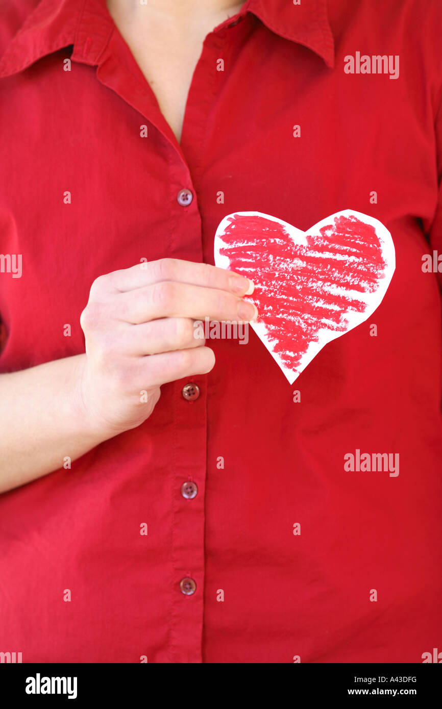 Woman holding paper heart cutout over chest Stock Photo
