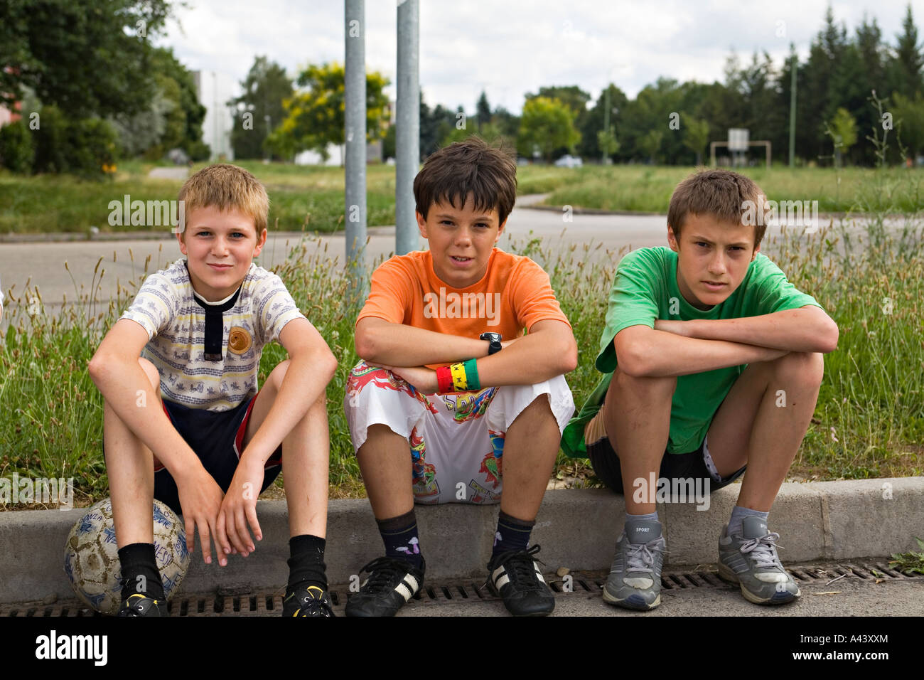 SLOVAKIA Sturovo Three young boys sit on curb with soccer ball Stock Photo  - Alamy