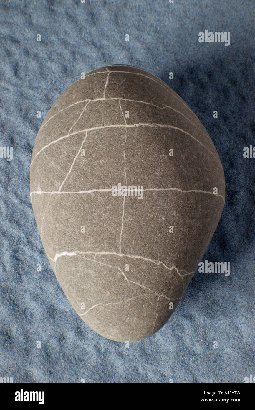 Elliptical ancient stone with irregular geometric markings on grey background. Stock Photo