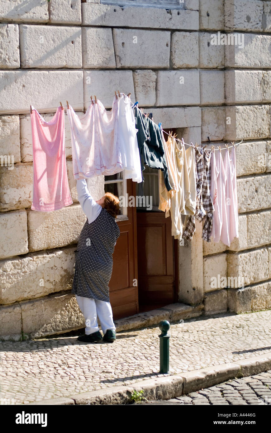 Woman hanging out washing to dry outside on the pavement in the ALFAMA  district of Lisbon Portugal Stock Photo - Alamy
