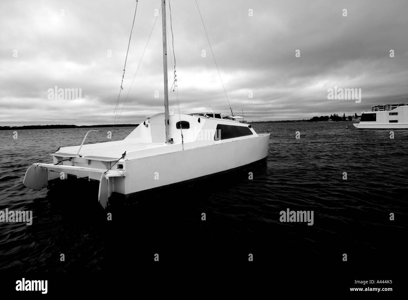 CATAMARRAN SAILING BOAT MOORED ON A CALM MORNING HORIZONTAL BAPDB4973 BLACK AND WHITE Stock Photo