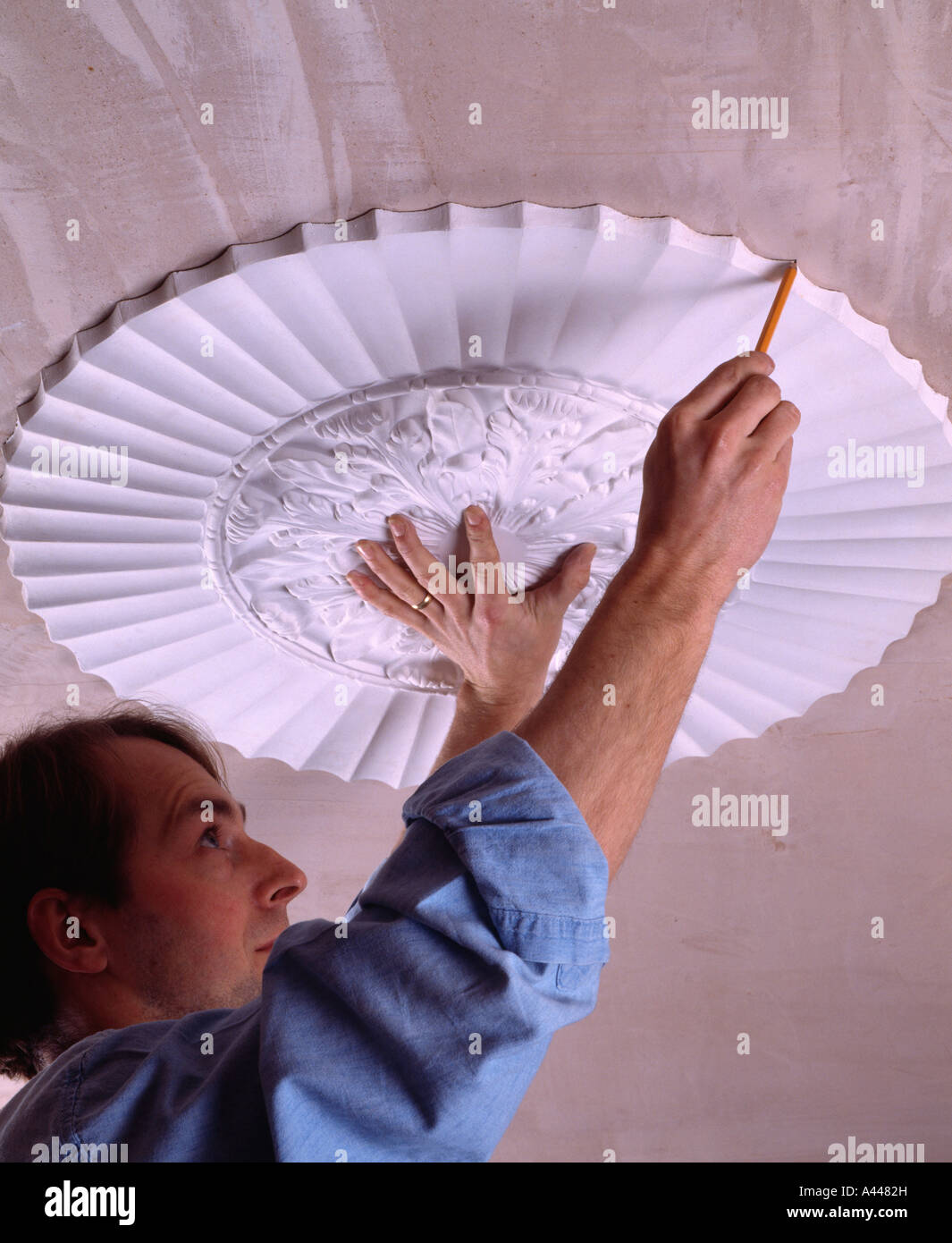 Close Up Of Man Replacing Plaster Ceiling Rose Stock Photo