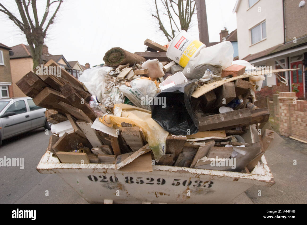 Unlicensed and Overloaded Skip in road, full of DIY rubbish outside