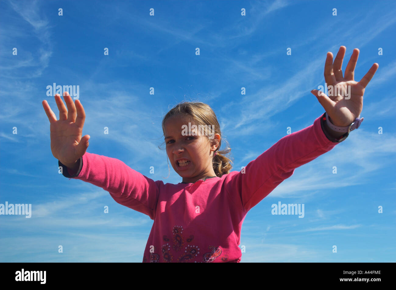 girl child with zonky expression big sky behind arms akimbo Stock Photo