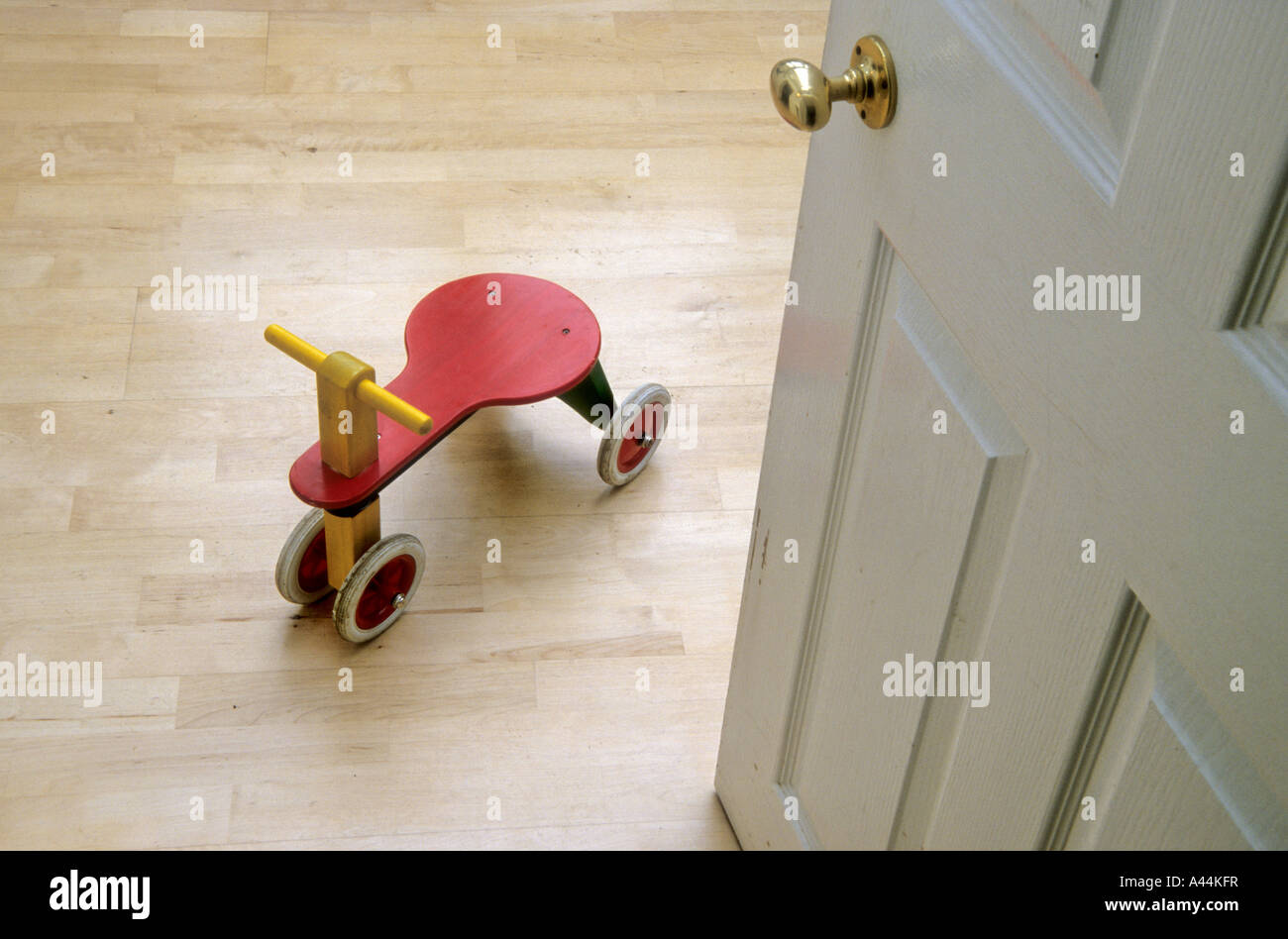 wooden tricycle on wooden floor with door ajar Stock Photo Alamy
