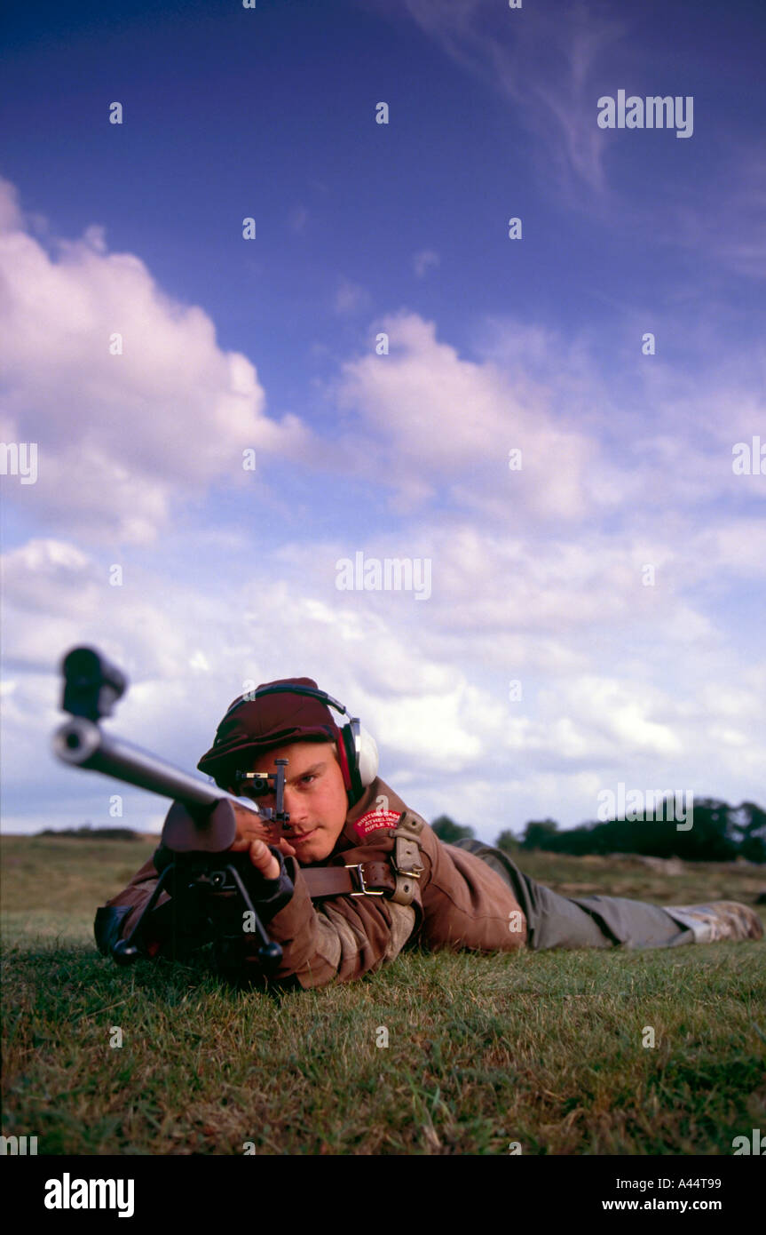 amateur target shooter takes aim with rifle at Bisley shooting range UK