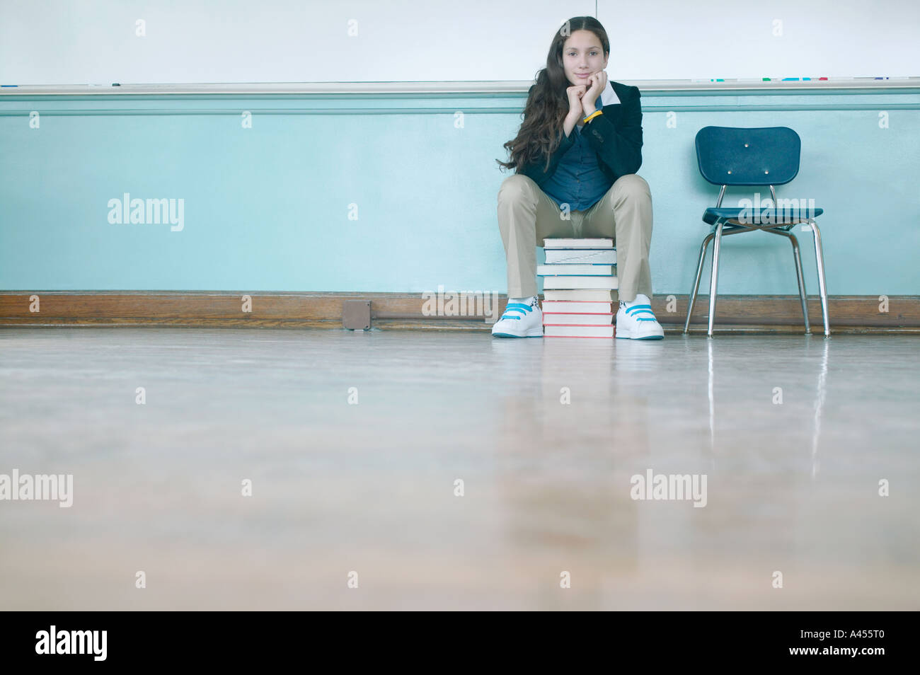 Teenage girl sitting on stack of books Stock Photo - Alamy