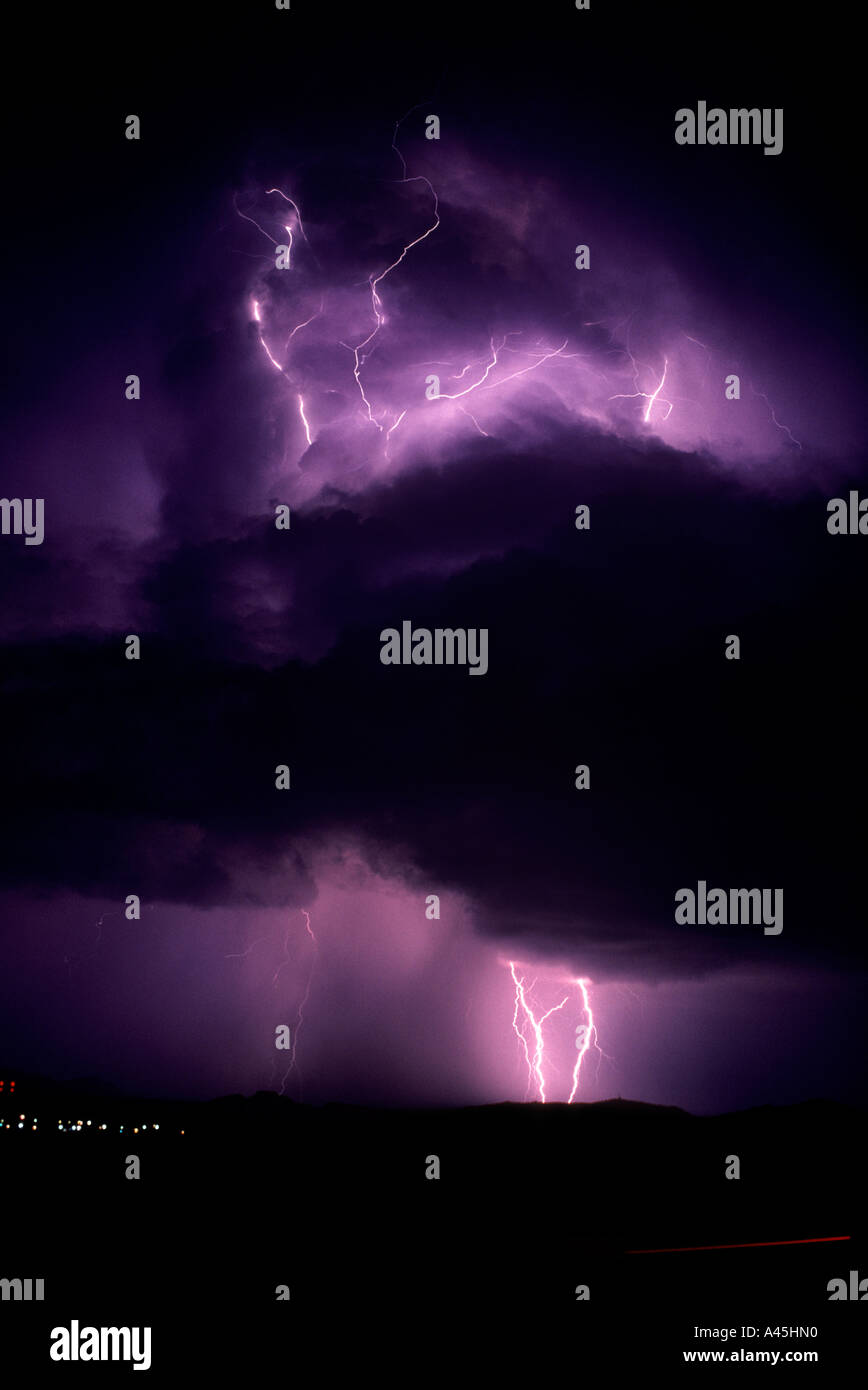 Lightning strikes against a black and purple sky and reflects on water in the foreground in Southern Arizona, USA. Stock Photo
