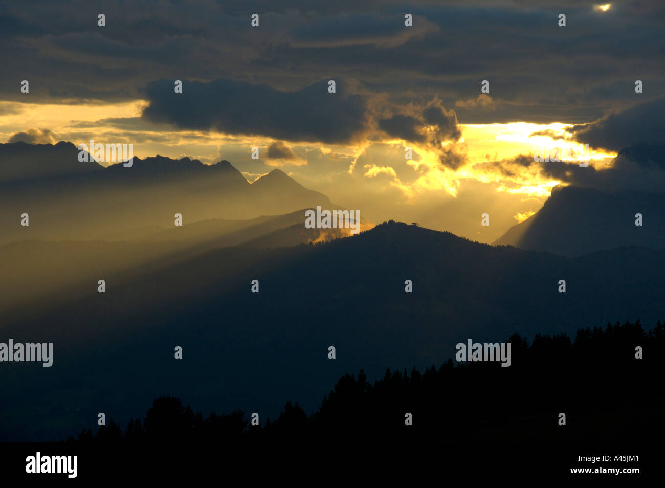Evening sky yellow sunrays shine through dark skies Haute-Savoie France Stock Photo