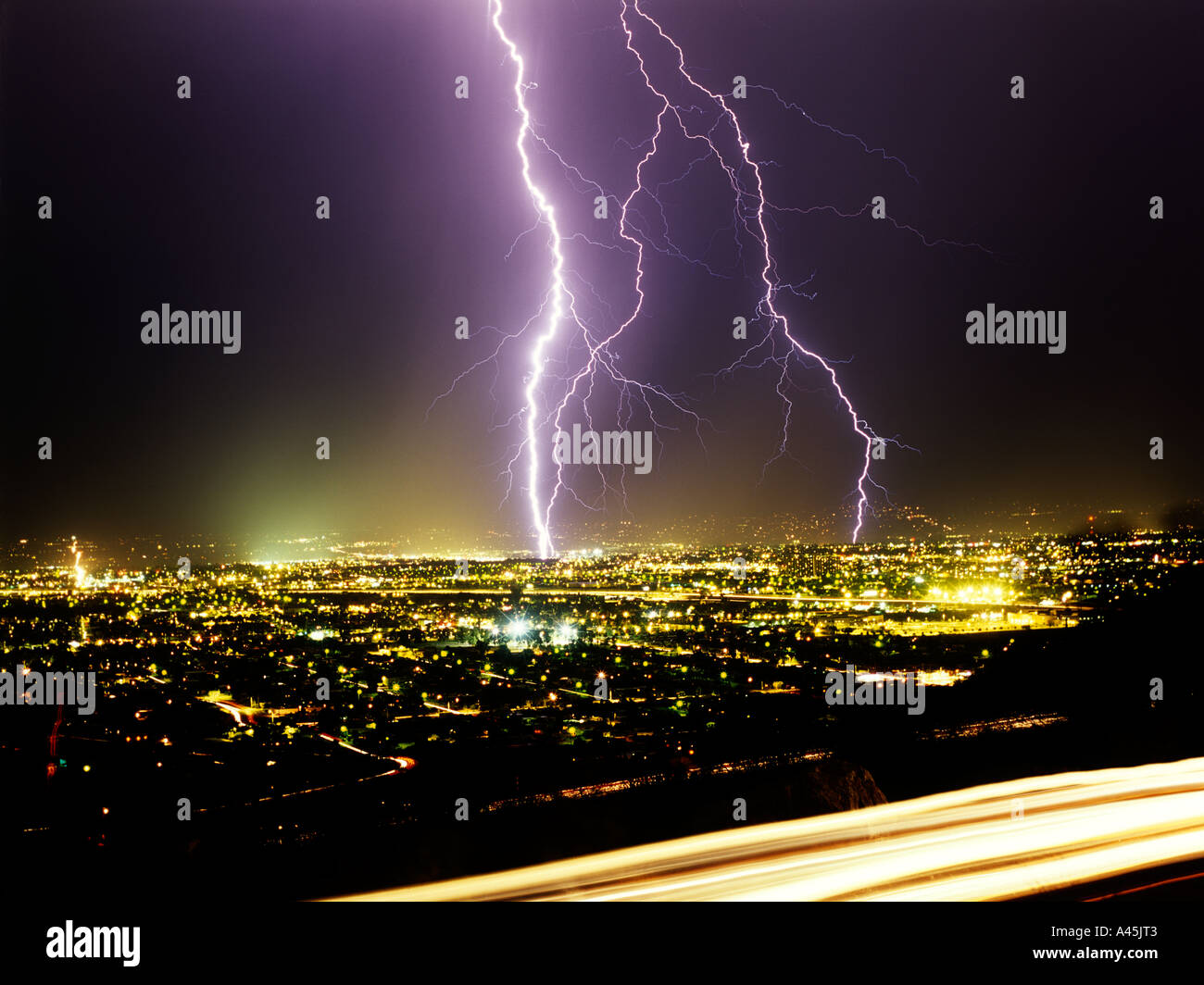 Lightning strikes from a black sky over a glowing cityscape in Southern Arizona, USA. Stock Photo